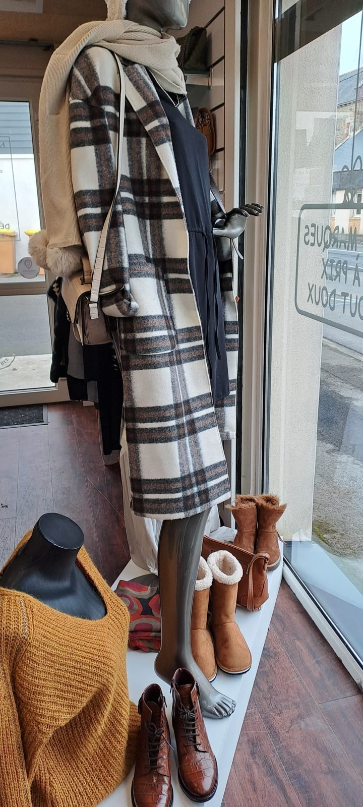 Manteau à carreaux, écharpe et bottines en vitrine